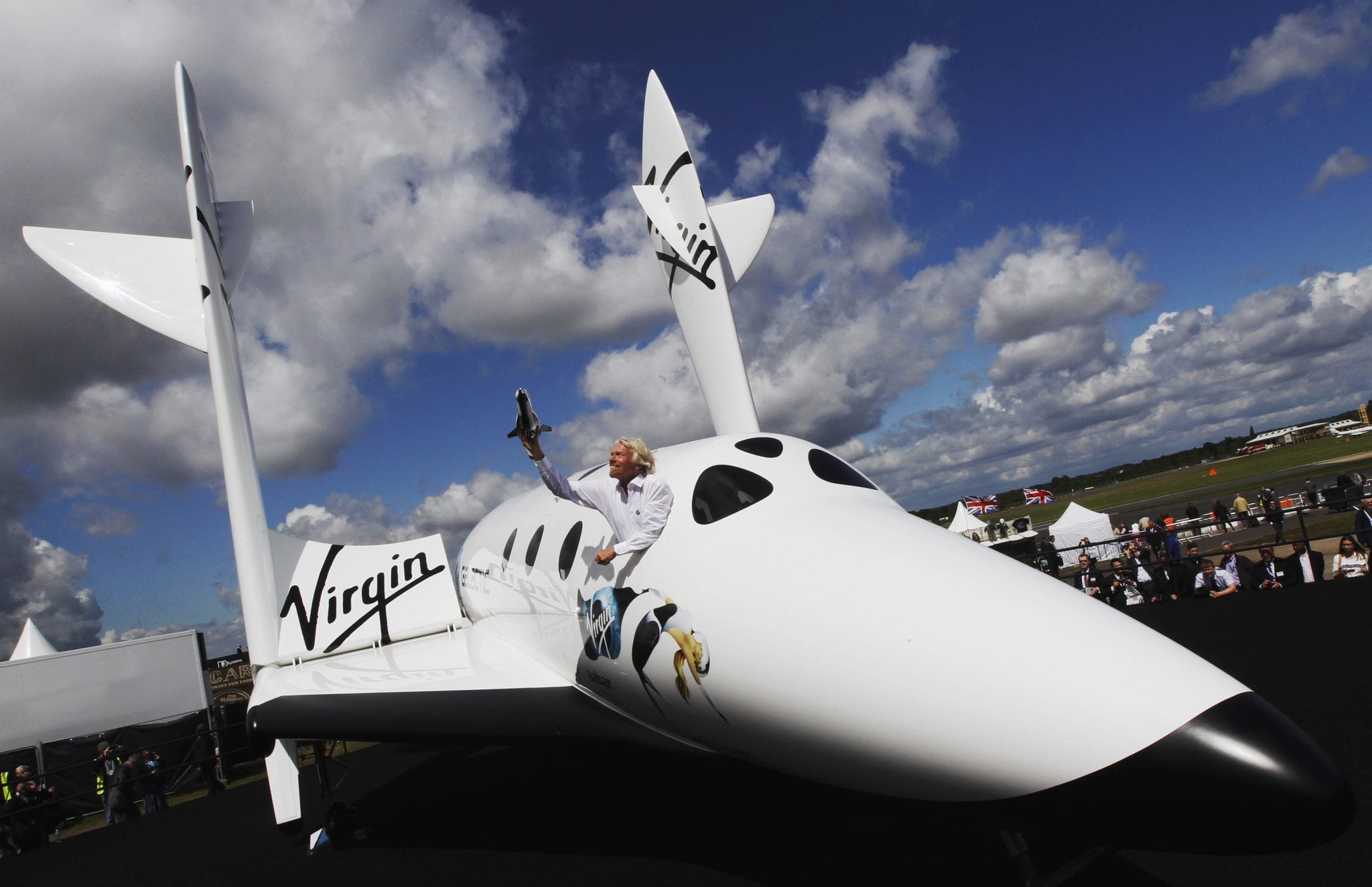 File photo of entrepreneur Branson waving a model of the LauncherOne cargo spacecraft from a window of an actual size model of SpaceShipTwo on display. 