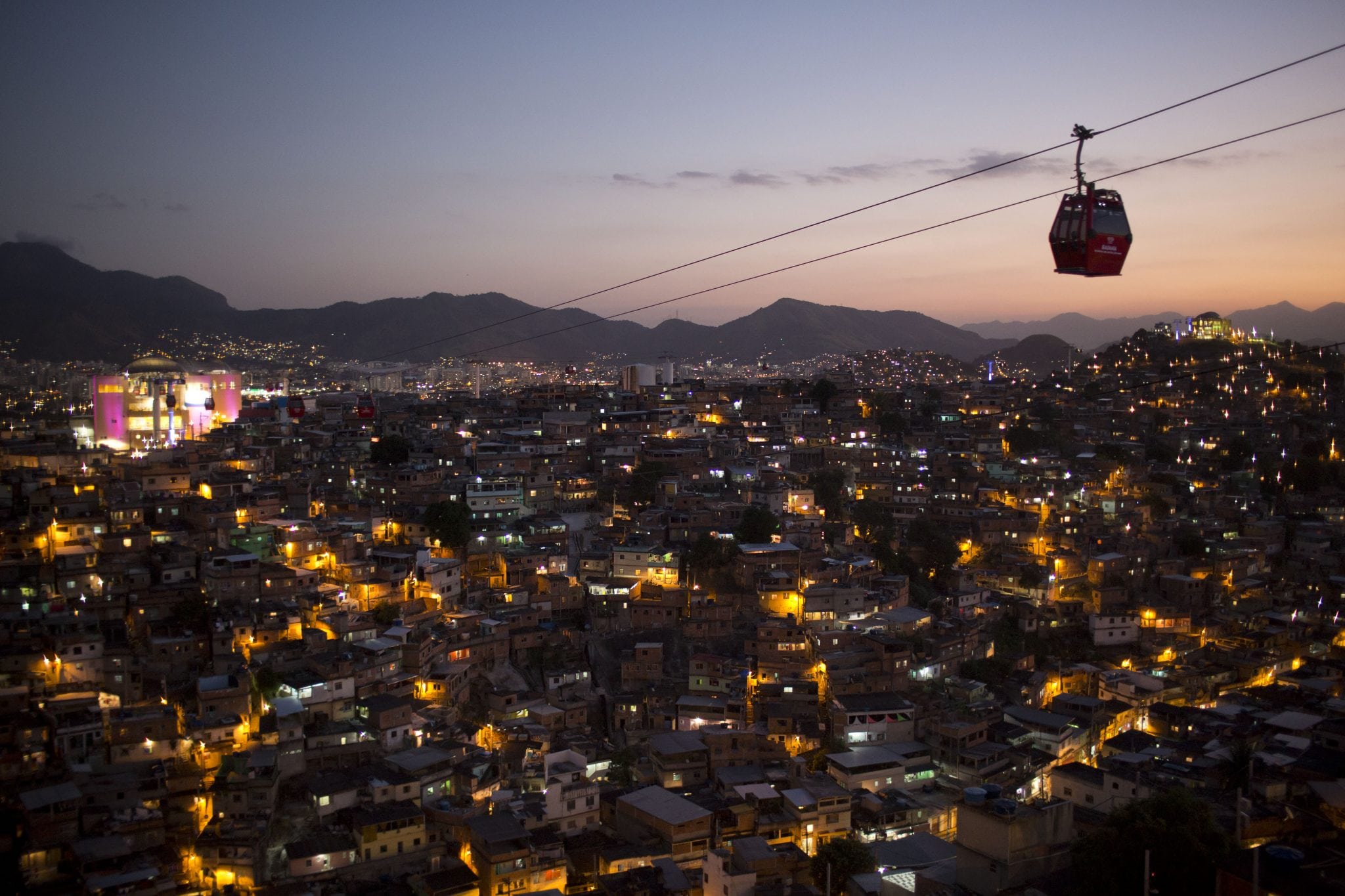 n this May 10, 2013 photo, homes are lit at night as cable-cars move commuters over the Complexo do Alemao complex of shantytowns in Rio de Janeiro, Brazil. The cable-car system linking six of its hilltops over a 3.5-kilometer (2.3-mile) route has become a popular tourist attraction. 
