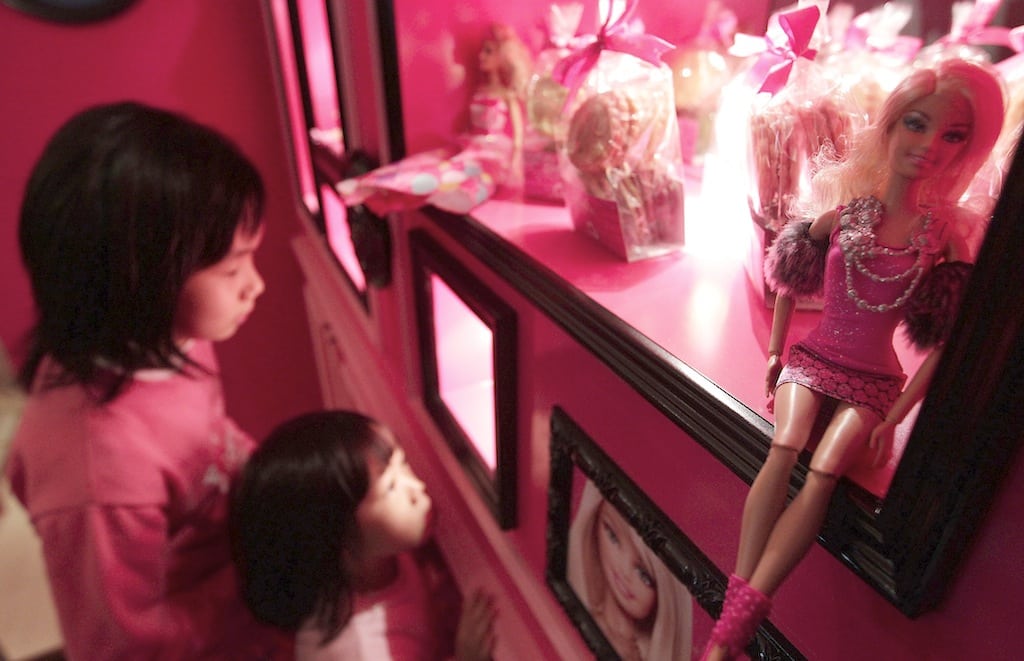 Girls look at Barbie dolls on display during the media preview of a Barbie-themed cafe in Taipei January 30, 2013. That Barbie is a global attraction was evident as Barbie The Dreamhouse Experience opened in South Florida this week and will debut in Germany next week. 