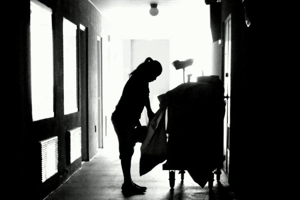 A housekeeper pulls trash bags out of a cart. 