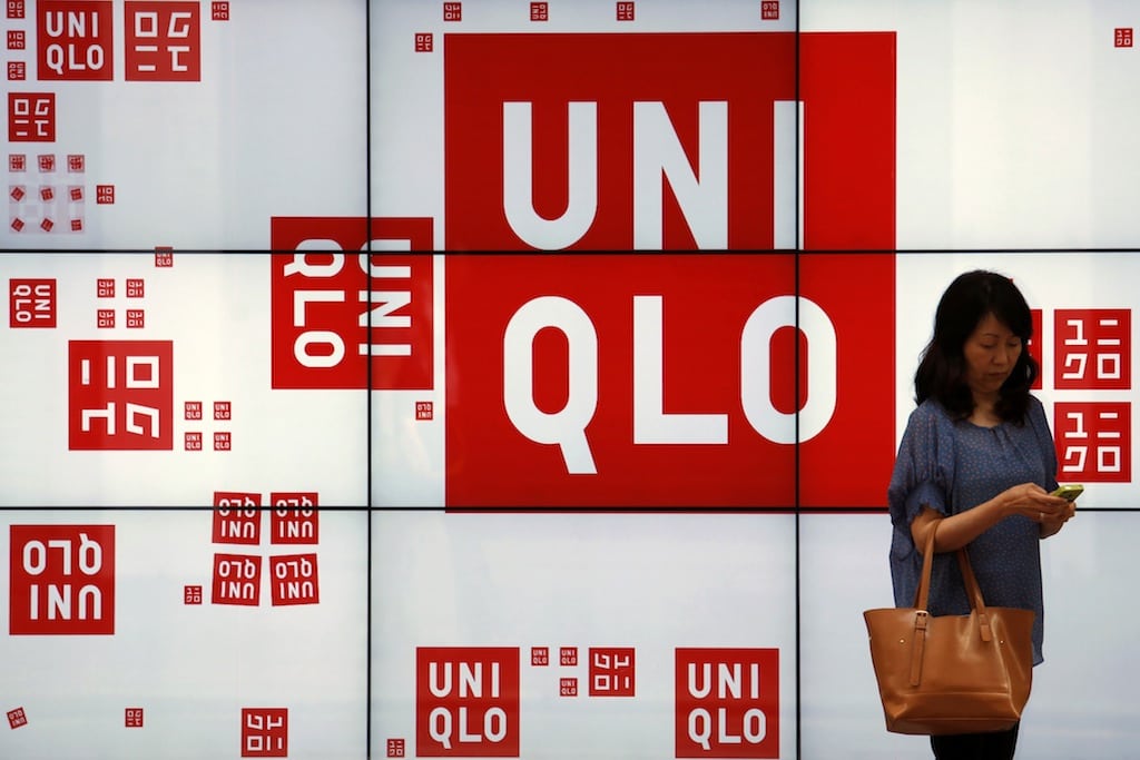 A woman checks her phone in front of a panel outside the flagship store of Japanese fashion house Uniqlo at Hong Kong's Causeway Bay shopping district May 9, 2013. 
