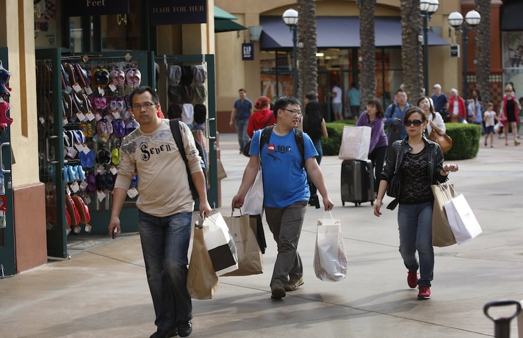 Chinese tourists tote merchandise as they shop at the Desert Hills Premium Outlets in Cabazon, California, on March 29, 2013. 