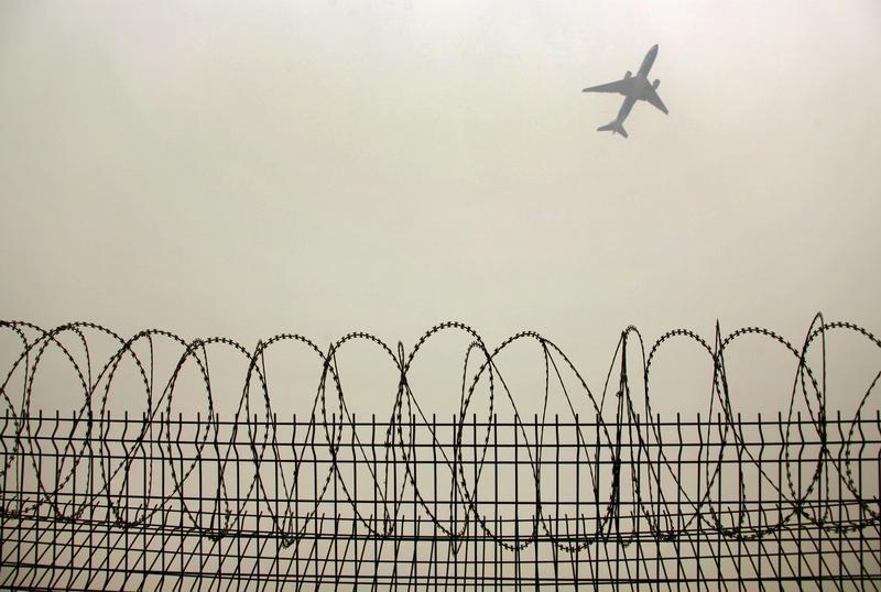 A plane flies in the polluted air above the airport fences in Beijing February 22, 2012.