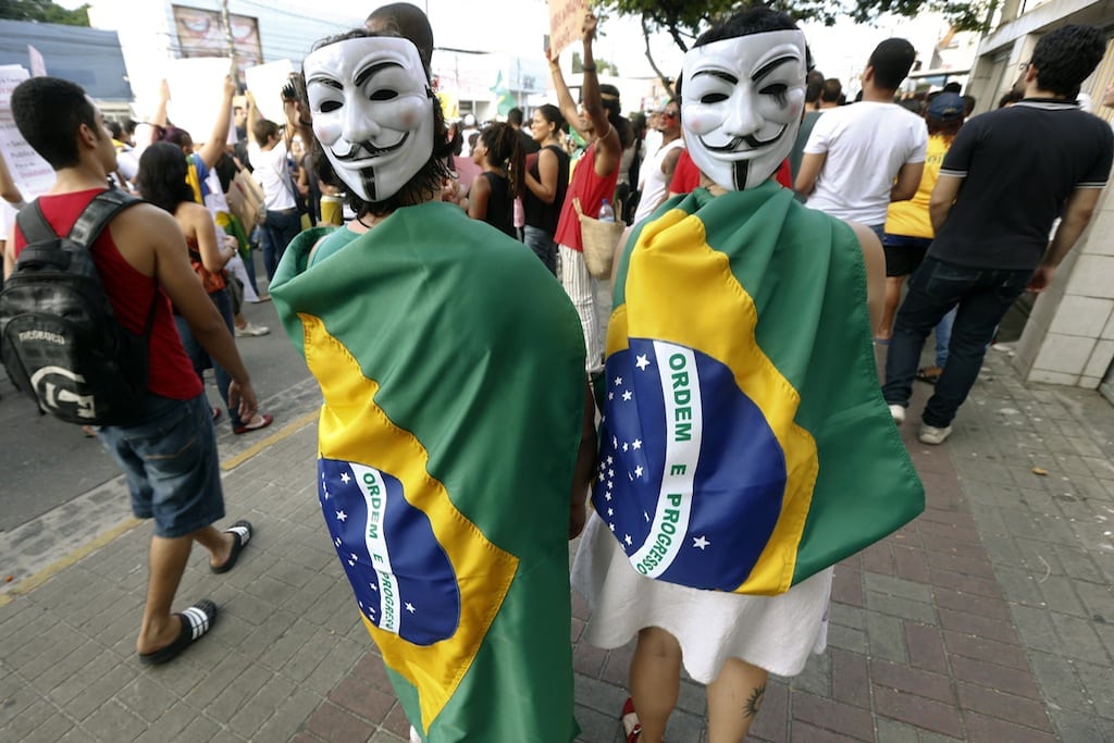 Demonstrators wearing Guy Fawkes masks at the back of their heads and draped with Brazilian national flags attend a protest against the Confederations Cup and the government of Brazil's President Dilma Rousseff in Recife City June 20, 2013. 