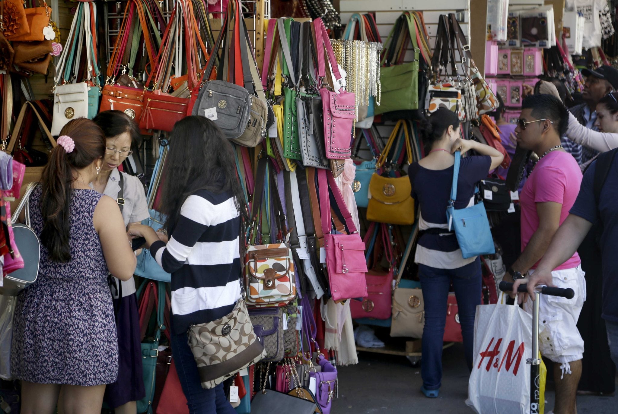 Pedestrians shop for purses and other merchandise on Canal Street in New York, Tuesday, June 4, 2013. 