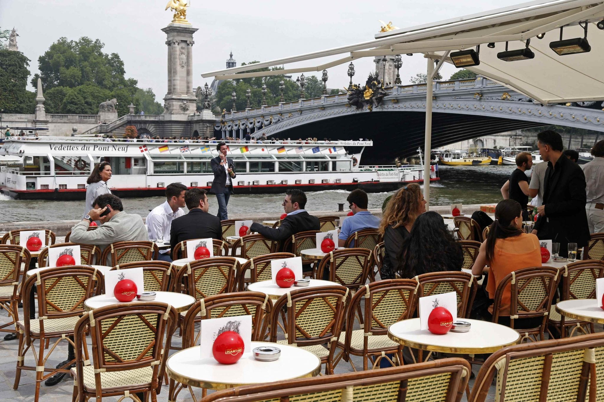 People sit at a terrace cafe near the Alexandre III bridge on the opening day of the new pedestrian walkway area between the Orsay Museum and Alma Bridge on the left bank of the River Seine in Paris June 19, 2013. 