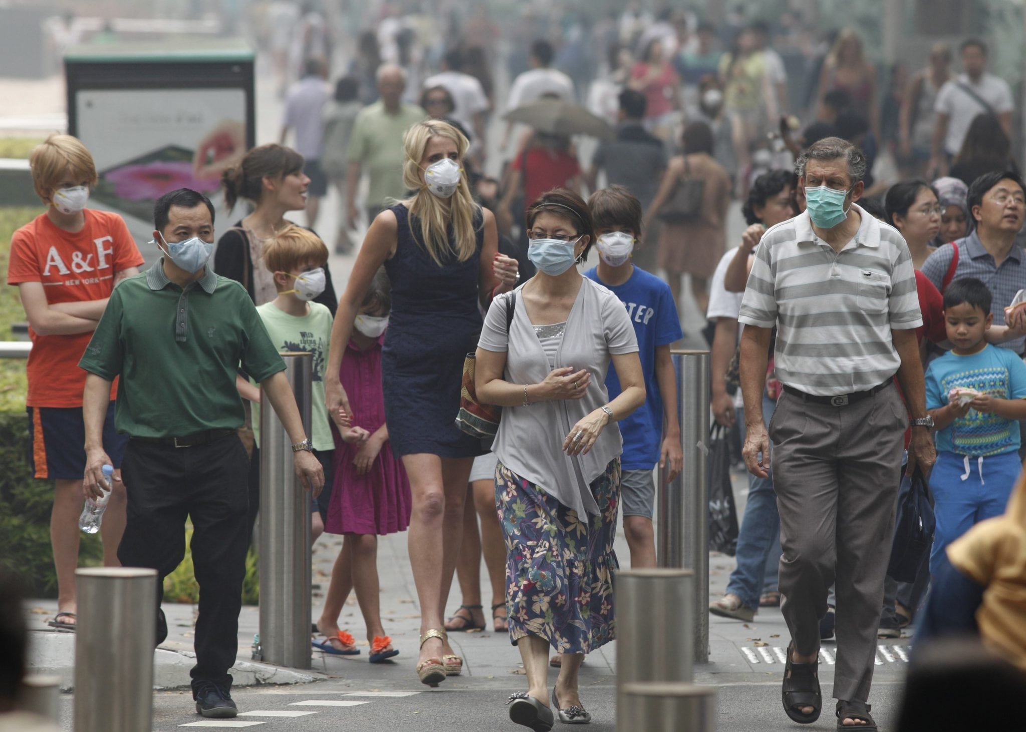 People wearing masks cross a street in Singapore's Orchard Road shopping area. 