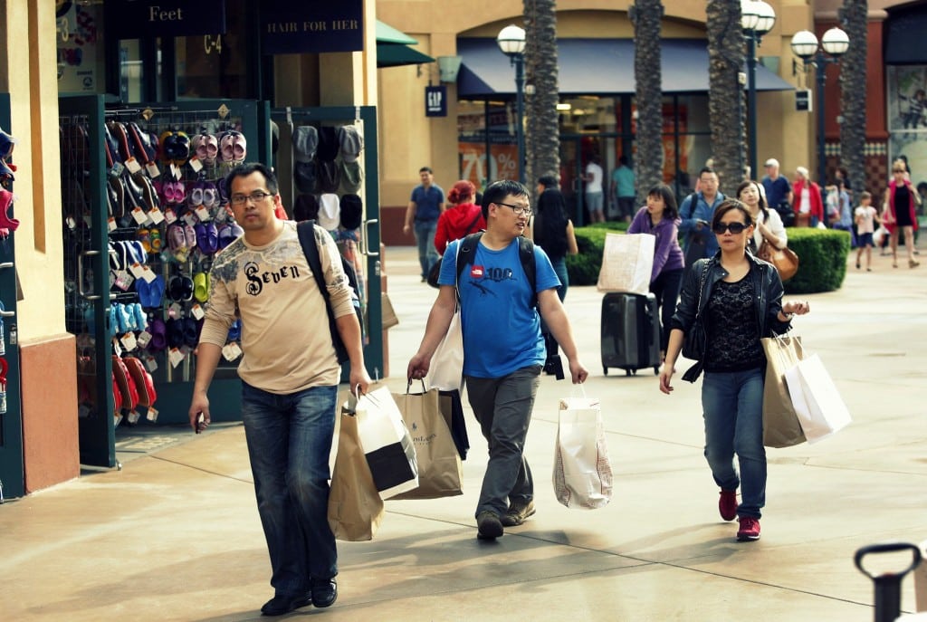 Chinese tourists tote merchandise as they shop at the Desert Hills Premium Outlets in Cabazon, California.
