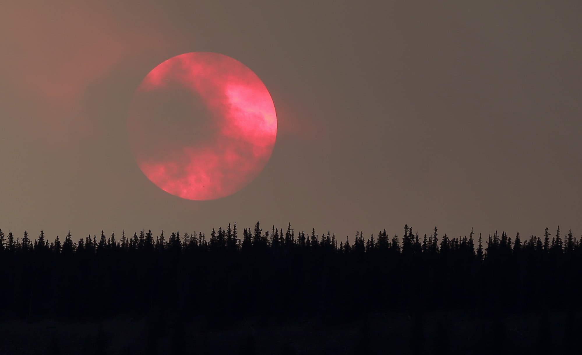 Wildfire smoke masks the sun as it sets over a ridge Saturday, June 22, 2013, near South Fork, Colo.
