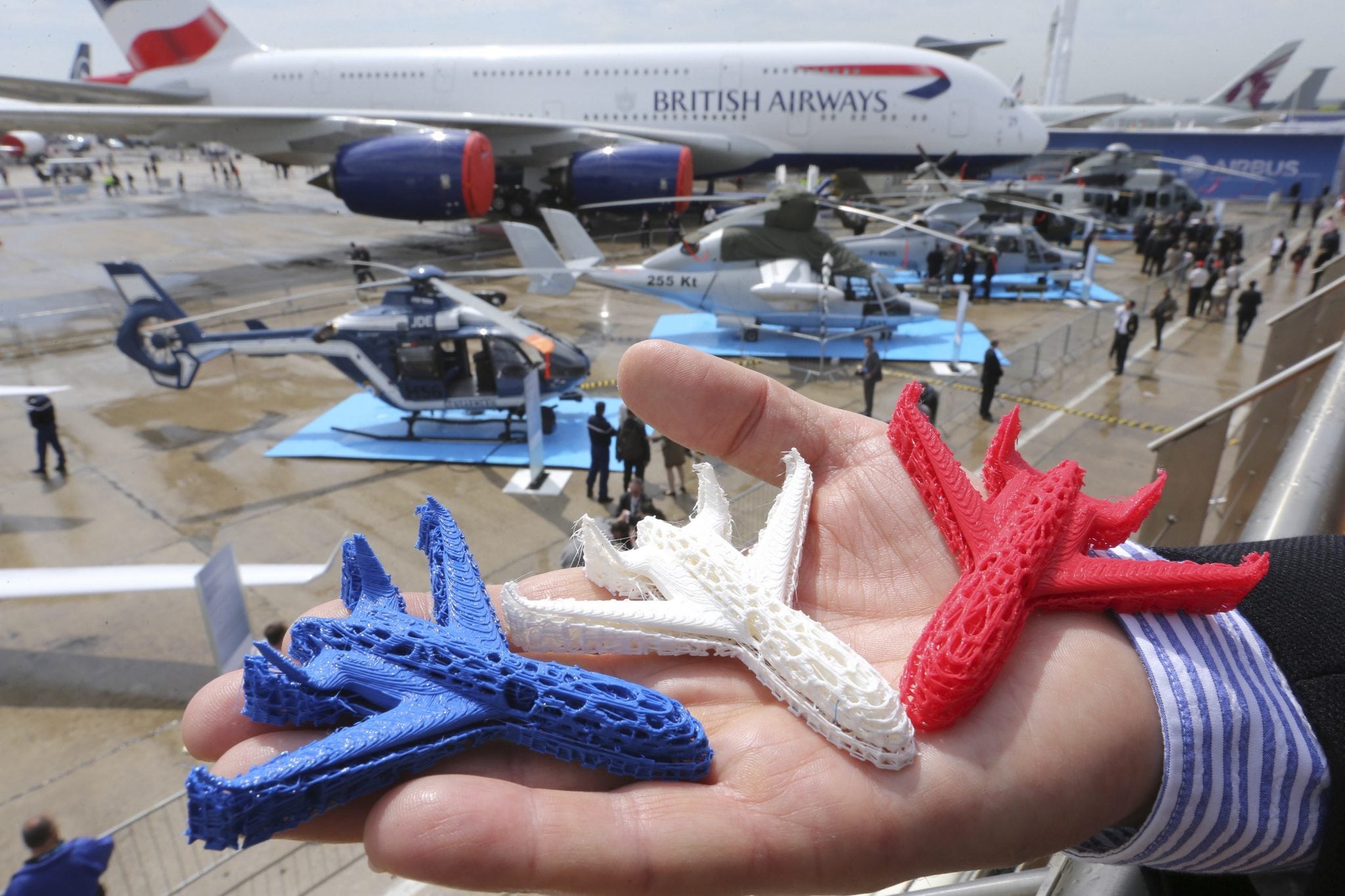 An Airbus employee presents three model airplanes in blue, white and red, made from starch using a 3D printing technique during the opening of 50th Paris Air Show. 