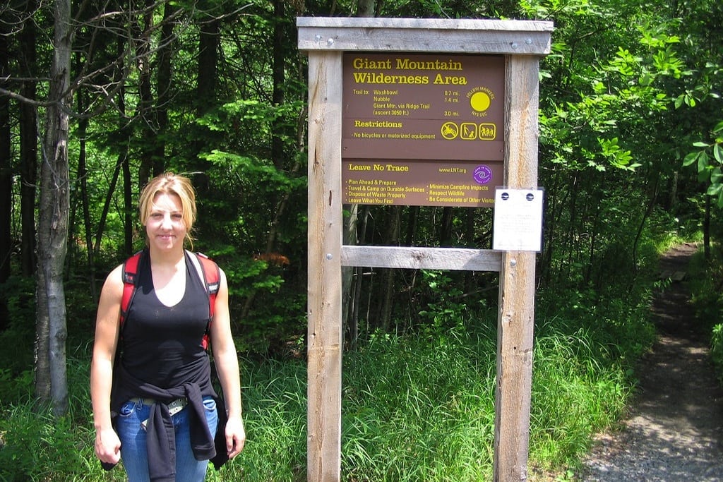 A park visitor stands in front of the Giant Mountain trailhead sign-in in Adirondack Park, New York. 