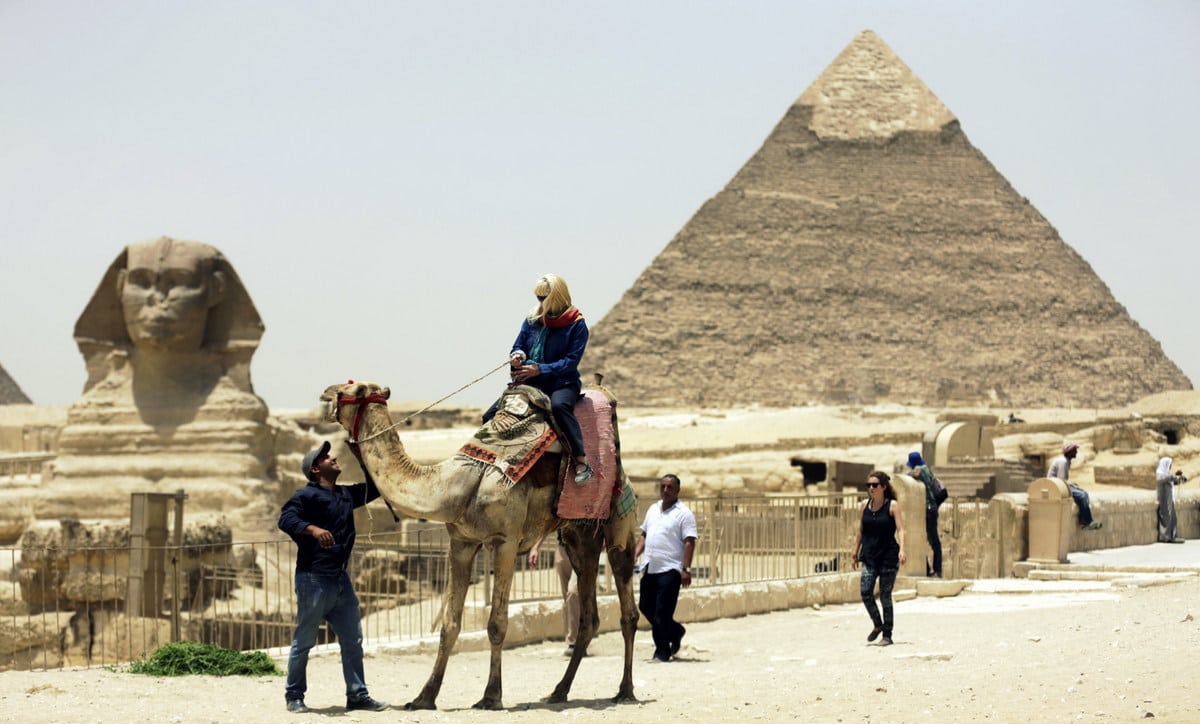 In this photo taken Friday, May 31, 2013, a tourist takes a camel ride at the Giza Pyramids in Giza, Egypt.