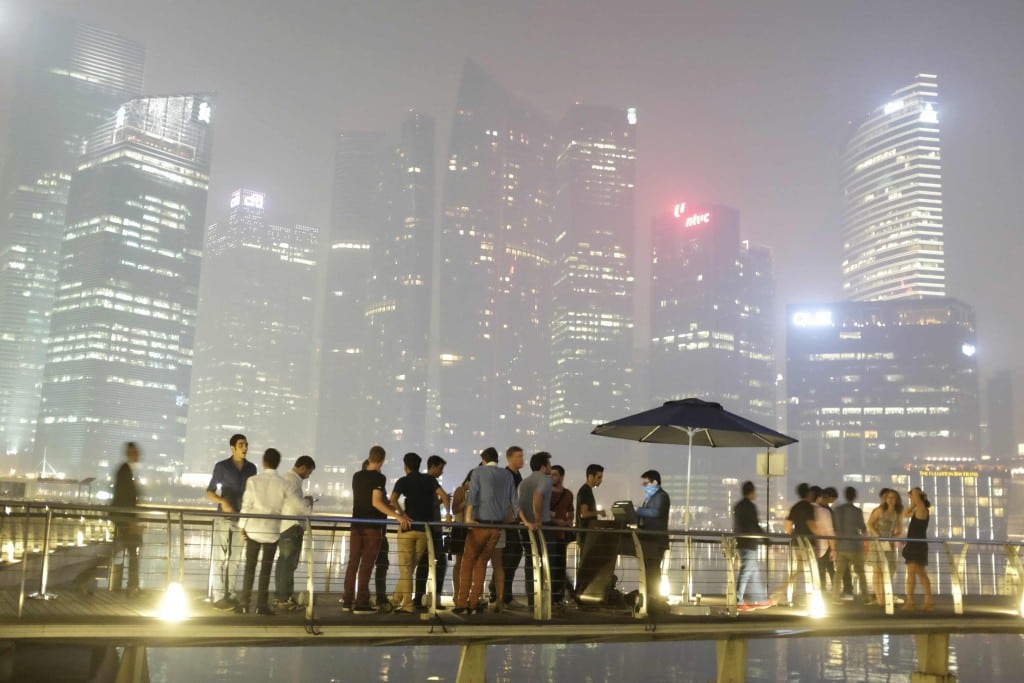Partygoers line up to enter a nightclub at Marina Bay Sands, as haze shrouds the skyline of Singapore in the background, late June 19, 2013.