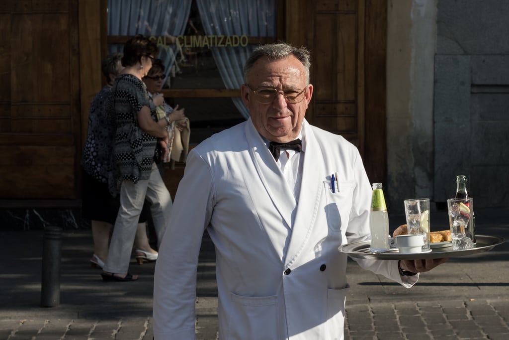 A waiter brings drinks to an outdoor table in Madrid. 