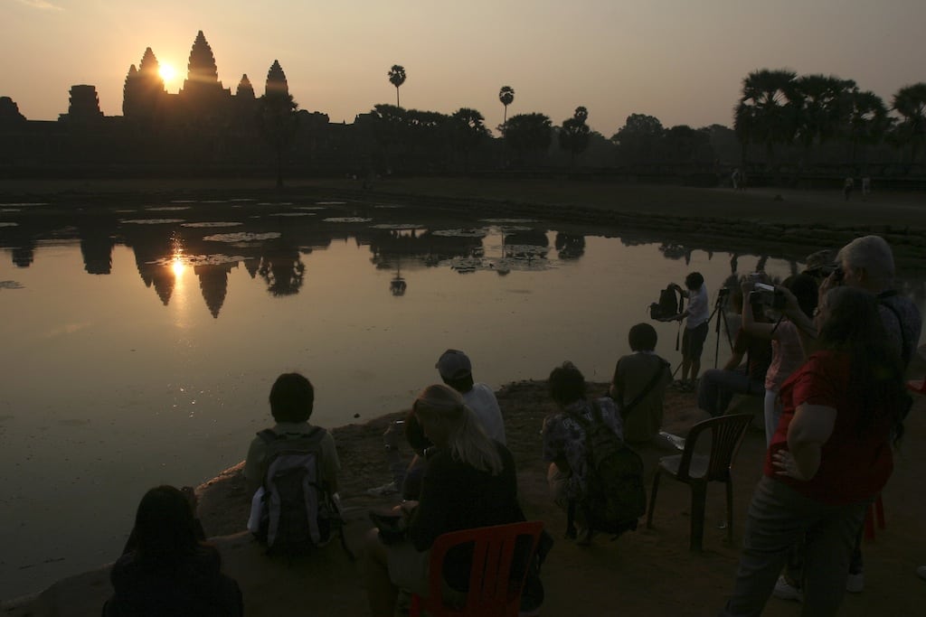 In this March 30, 2008 photo, tourists watch the sunrise at the famed Angkor Wat temple in Siem Reap province, Cambodia. 