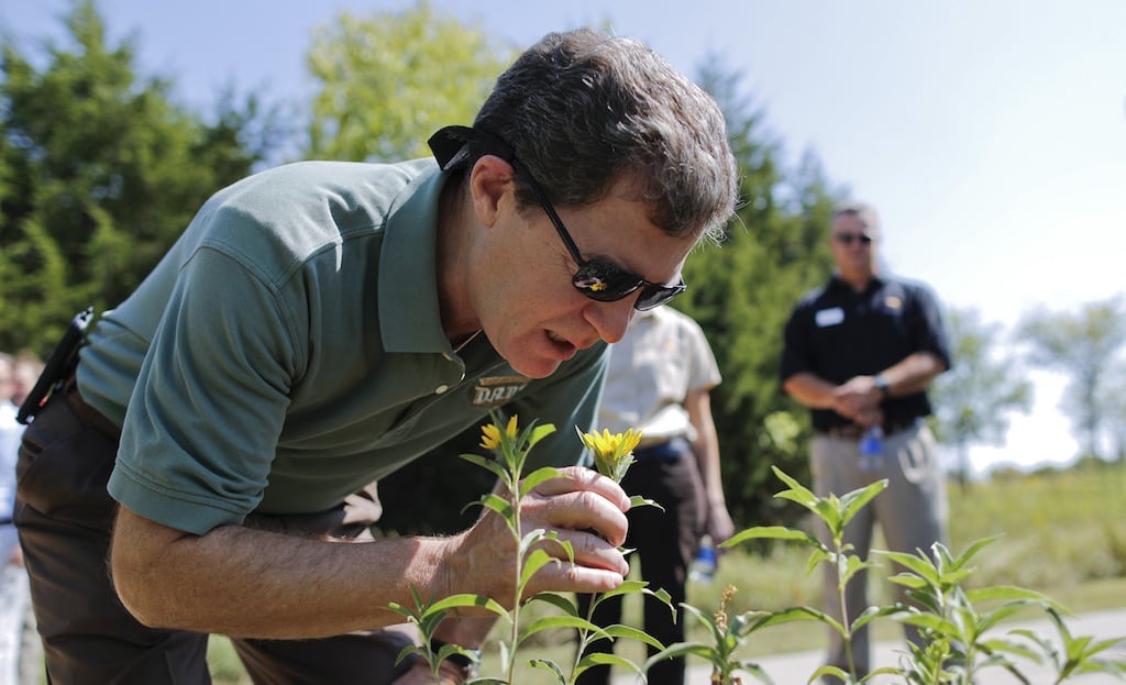 Kansas governor Sam Brownback smells a sunflower while on a walking tour of the Great Plains Nature Center in Wichita, Kansas, on Wednesday, September 19, 2012. Brownback announced the formation of the Kansas Ecotourism Steering Committee to help guide ecotourism efforts in the state. 