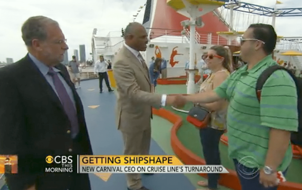 Peter Greenberg (left) and new Carnival Corp. CEO Arnold Donald greet passengers in a CBS This Morning segment about Carnival's turnaround. 