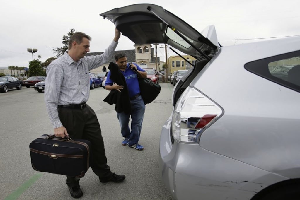 John Penny, left, and Marty Puranik load their luggage into a rental Prius at FlightCar in Millbrae, California.