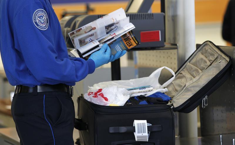 A TSA officer inspects items from a piece of luggage at Los Angeles International Airport in Los Angeles. 