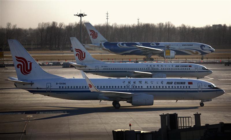 Air China planes pass each other on tarmac and runway at Beijing International Airport. 