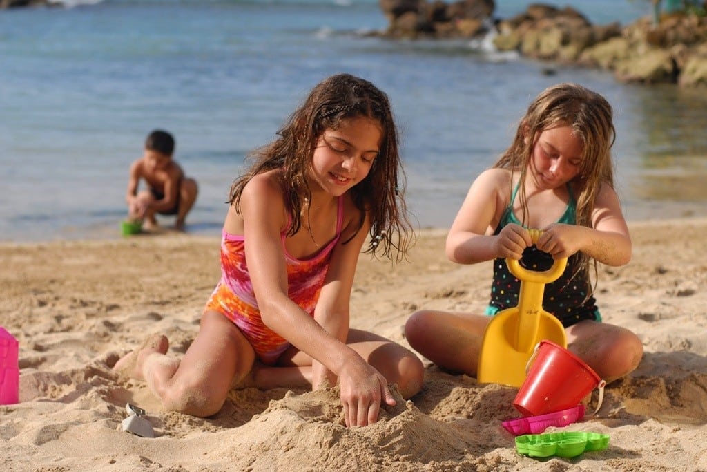 Kids build sand castles on the beach. 