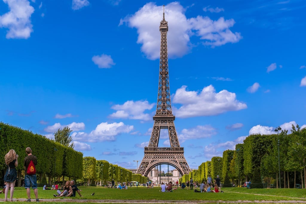 Visitors relax in front of the Eiffel Tower in Paris, France. 