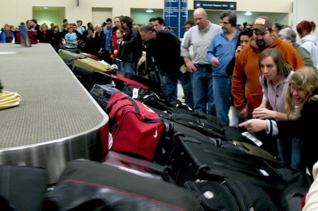 Passengers jostle for position at a luggage carousel at holiday time. 