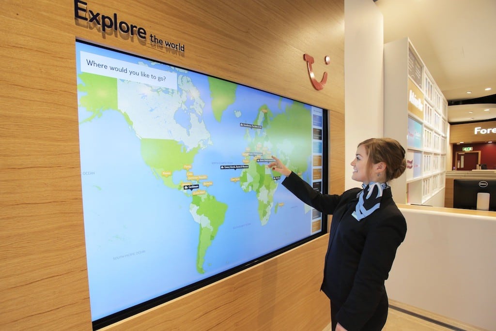 A Thomson travel agent shows travelers how to search on the store's digital map.