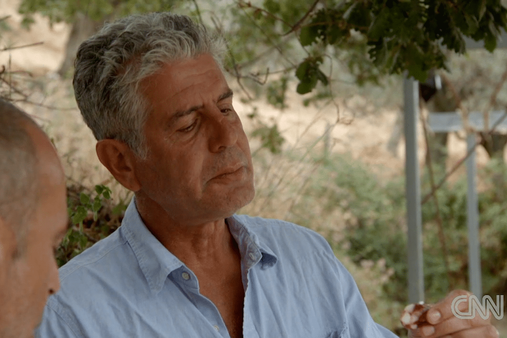 Anthony Bourdain eats salami at a family lunch. 