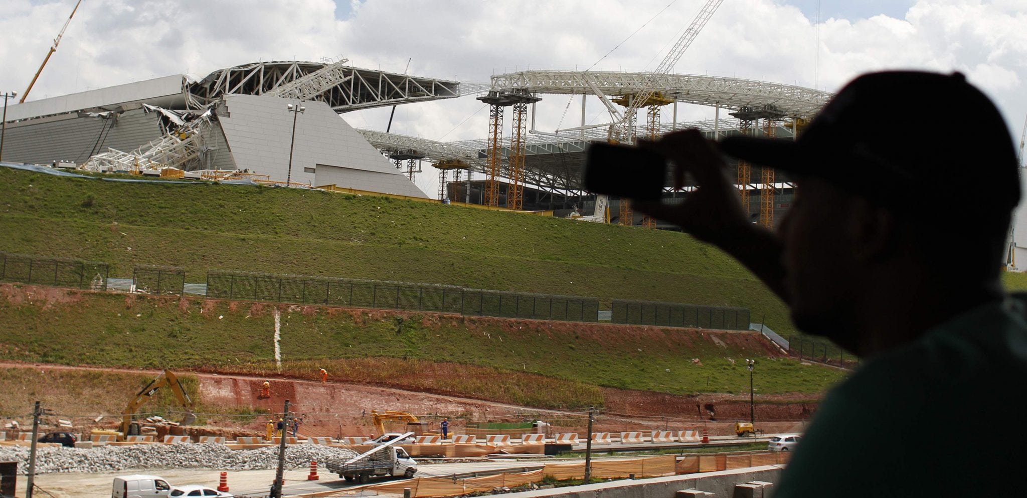 A man takes a picture of a crane that collapsed on the site of the Arena Sao Paulo stadium, known as "Itaquerao", which will host the opening soccer match of the 2014 World Cup, in Sao Paulo. 