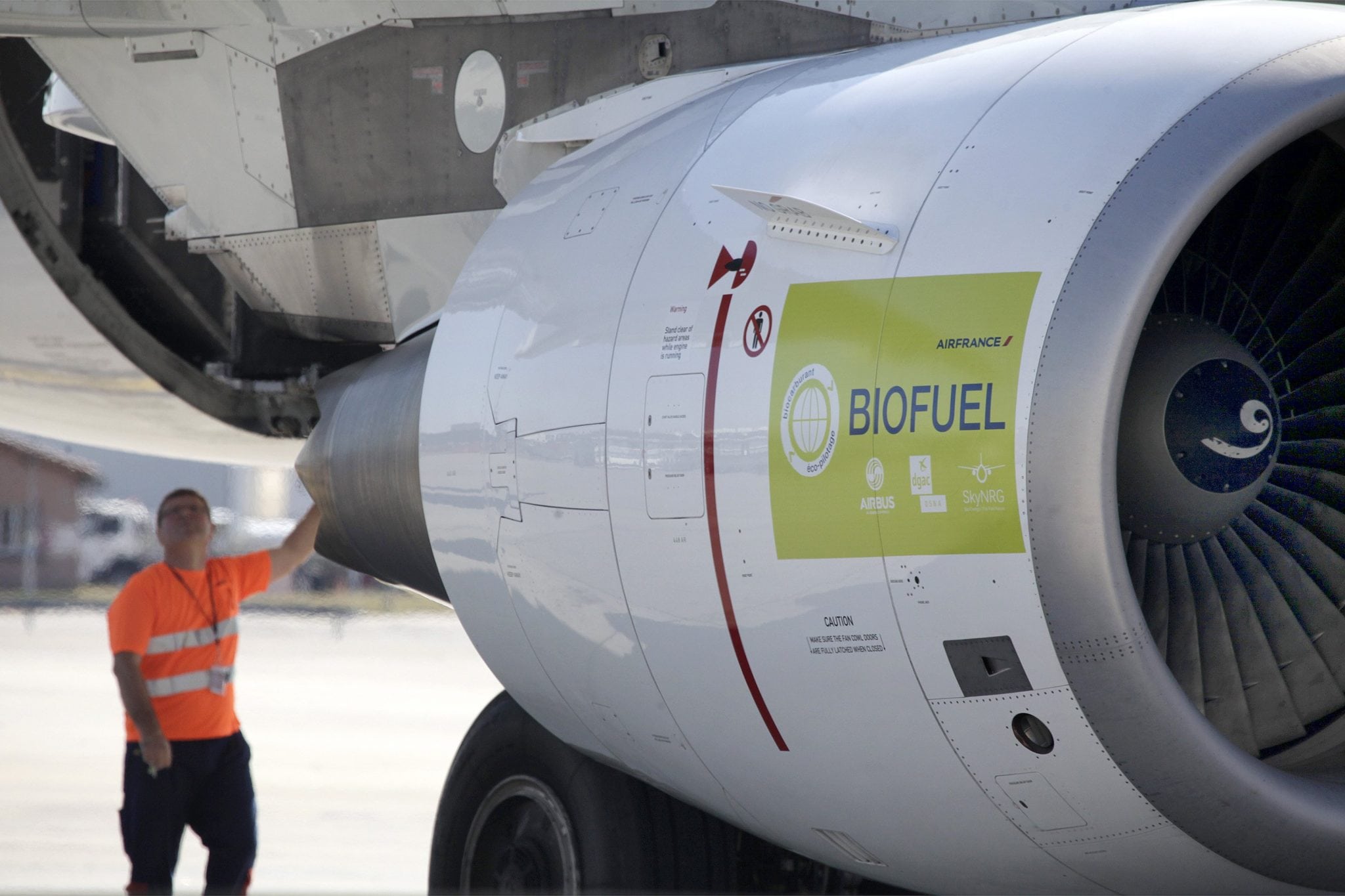 A technician works under the wing of an Air France's Airbus A321 green commercial plane at Toulouse-Blagnac Airport. 