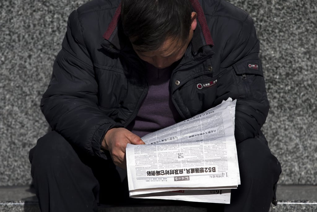 A Chinese man reads a newspaper which reports that U.S., Japan and South Korea sent flights through China's newly declared maritime air defense zone, in Beijing, China Friday, Nov. 29, 2013. China said it sent warplanes into the air defense zone days after the U.S., South Korea and Japan all sent flights through the airspace in defiance of rules Beijing says it has imposed in the East China Sea. 