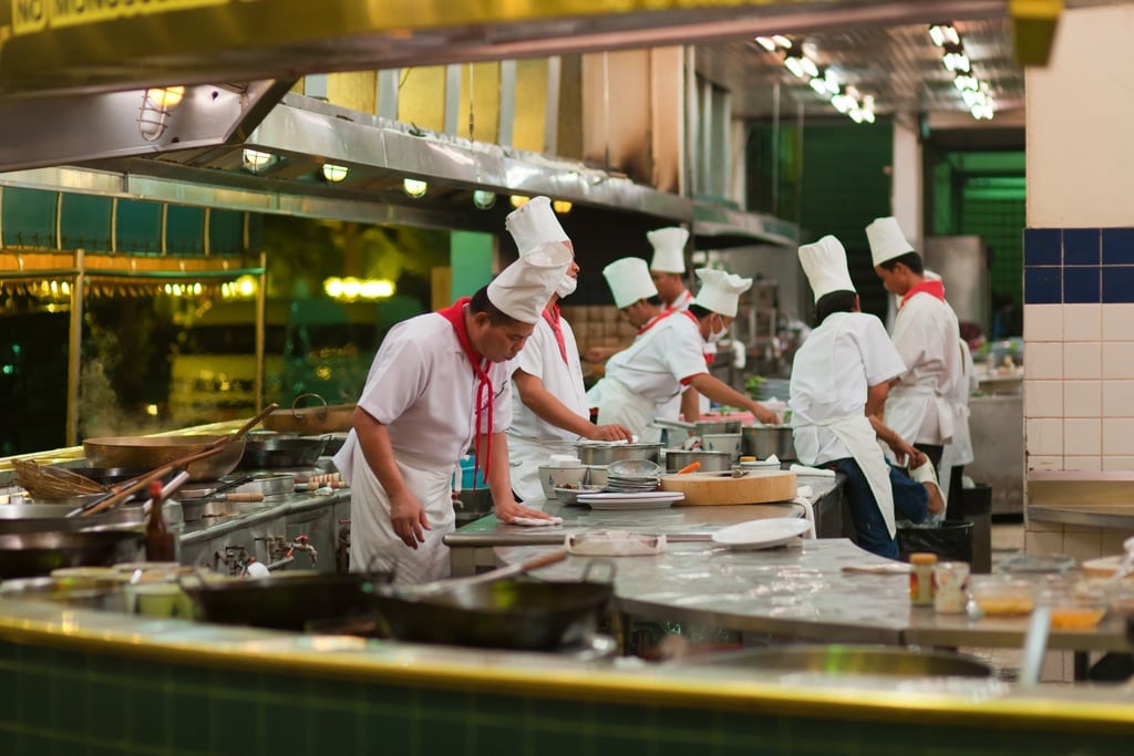 Chefs in an open kitchen restaurant at the seafood market in Bangkok, Thailand.