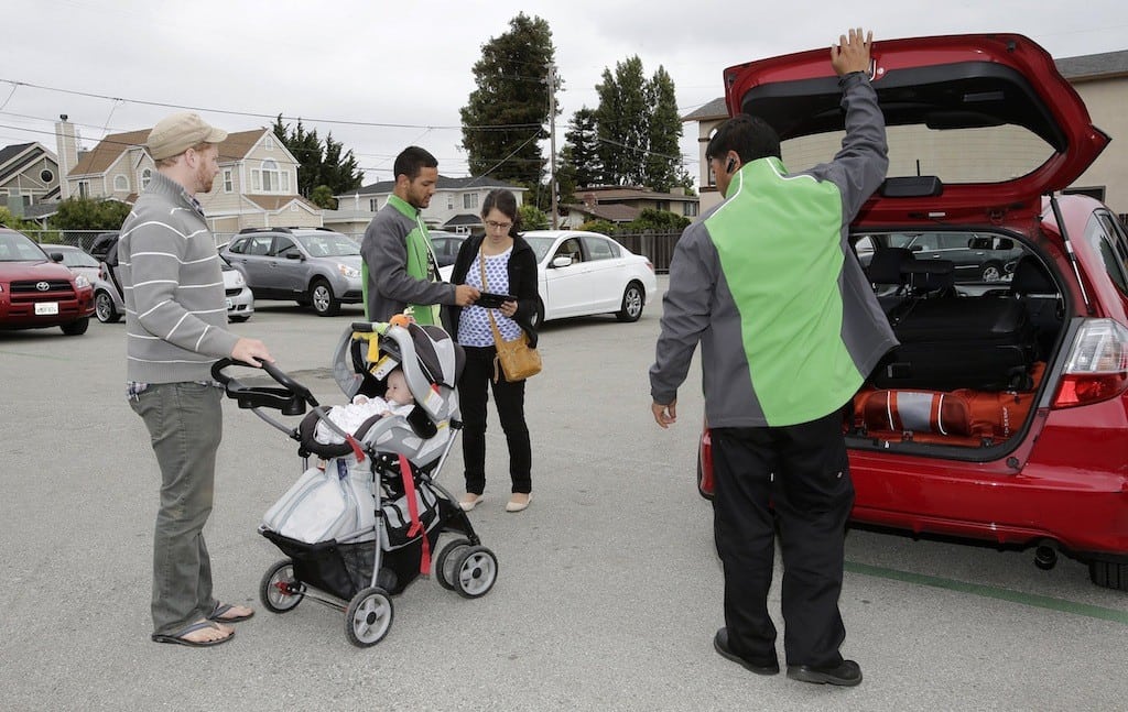 Avi Zinn, wife, Cory Isaacson and daughter Leah Zinn, 4-months-old, pick up their car at FlightCar in Millbrae, California, August 7, 2013. The couple live in Berkeley and have rented out their car at FlightCar three times. Helping them are FlightCar employees, Brendon Bucini and Ric Macapinlac, right.