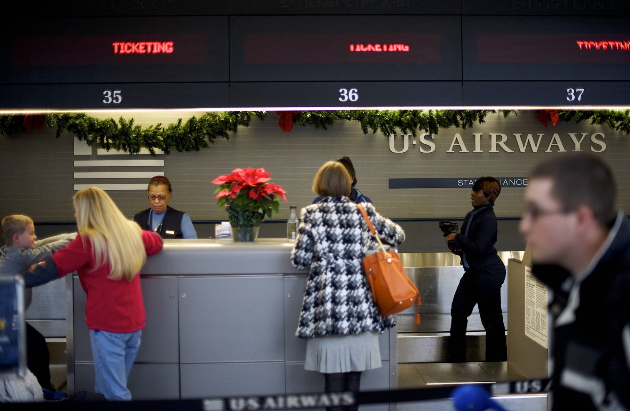 Employees check in travelers at the US Airways counters at Philadelphia International Airport. 