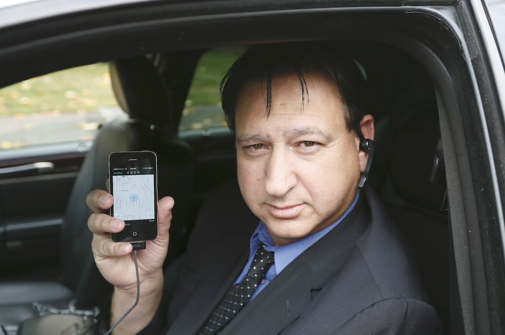 Limousine driver Shuki Zanna, 49, holds up his iPhone displaying transportation app Uber as he waits for customers in Beverly Hills, California, December 19, 2013. 