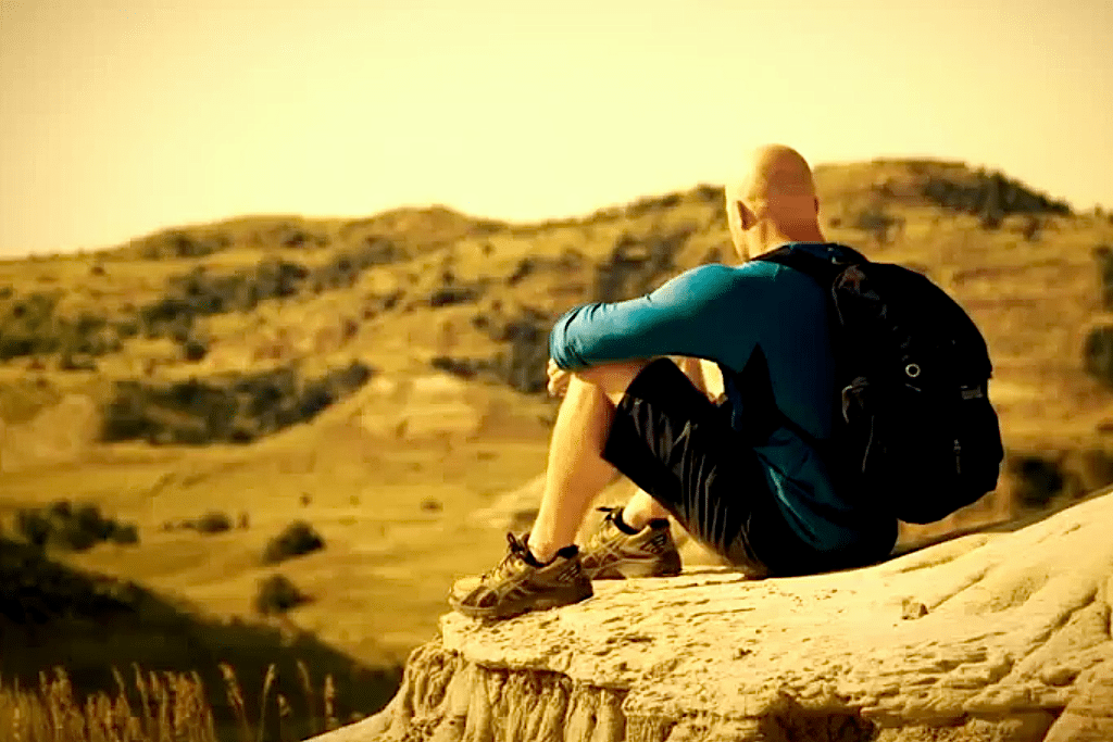 A man sits in Theodore Roosevelt National Park in North Dakota's new tourism ad.