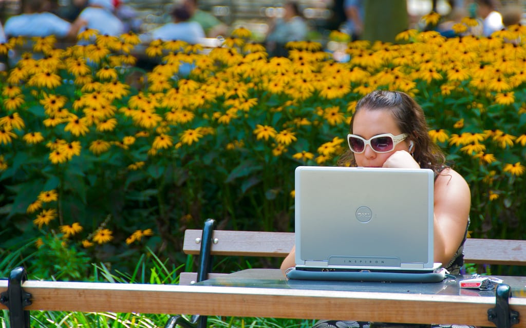A woman looks at her computer in Washington Square Park in New York City.