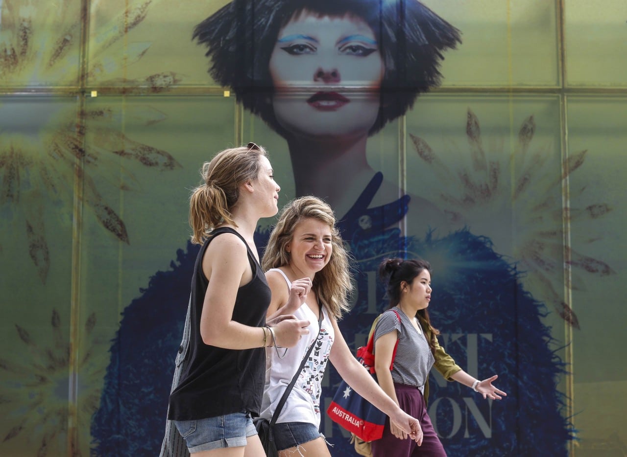 Tourists walk pass a billboard near a department store in Bangkok December 16, 2013. Developing economies like Thailand will see more international arrivals than advanced economies by 2020.