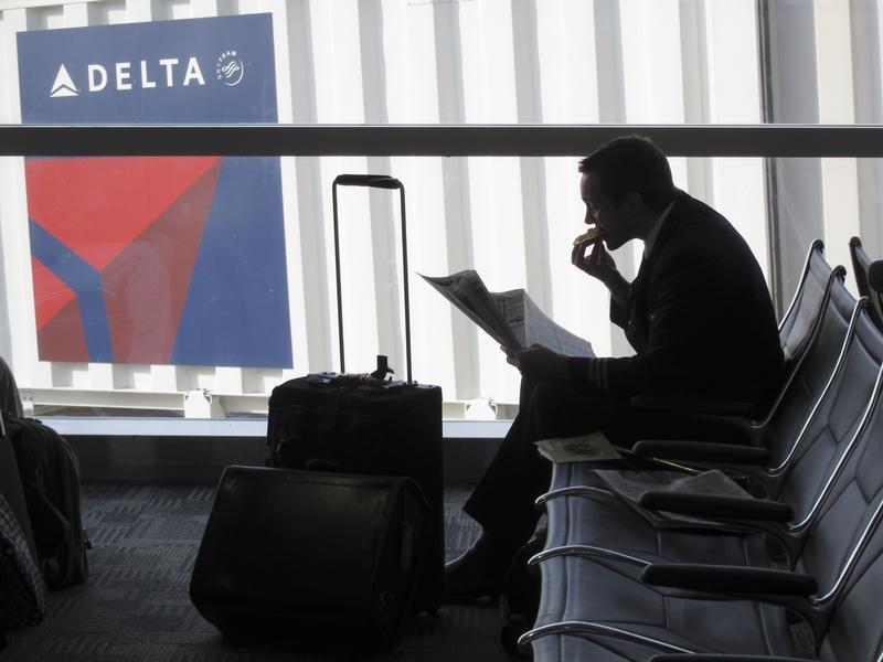 Passenger waits for his flight near a Delta Air Lines logo at Detroit Airport. 