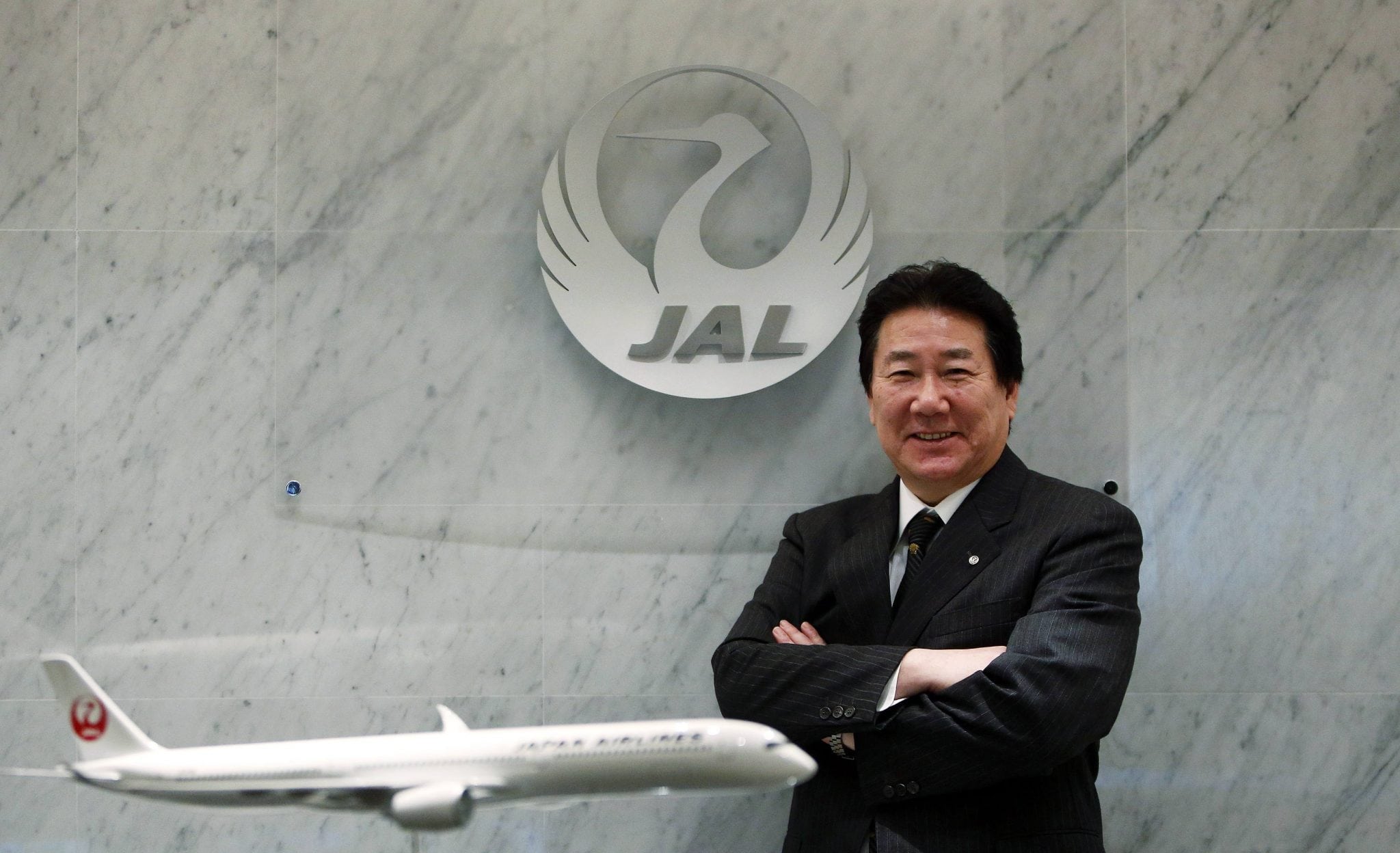 Yoshiharu Ueki, president of Japan Airlines, poses for photographs with a model of JAL's Airbus A350-900 after an interview with Reuters at its headquarters in Tokyo. 