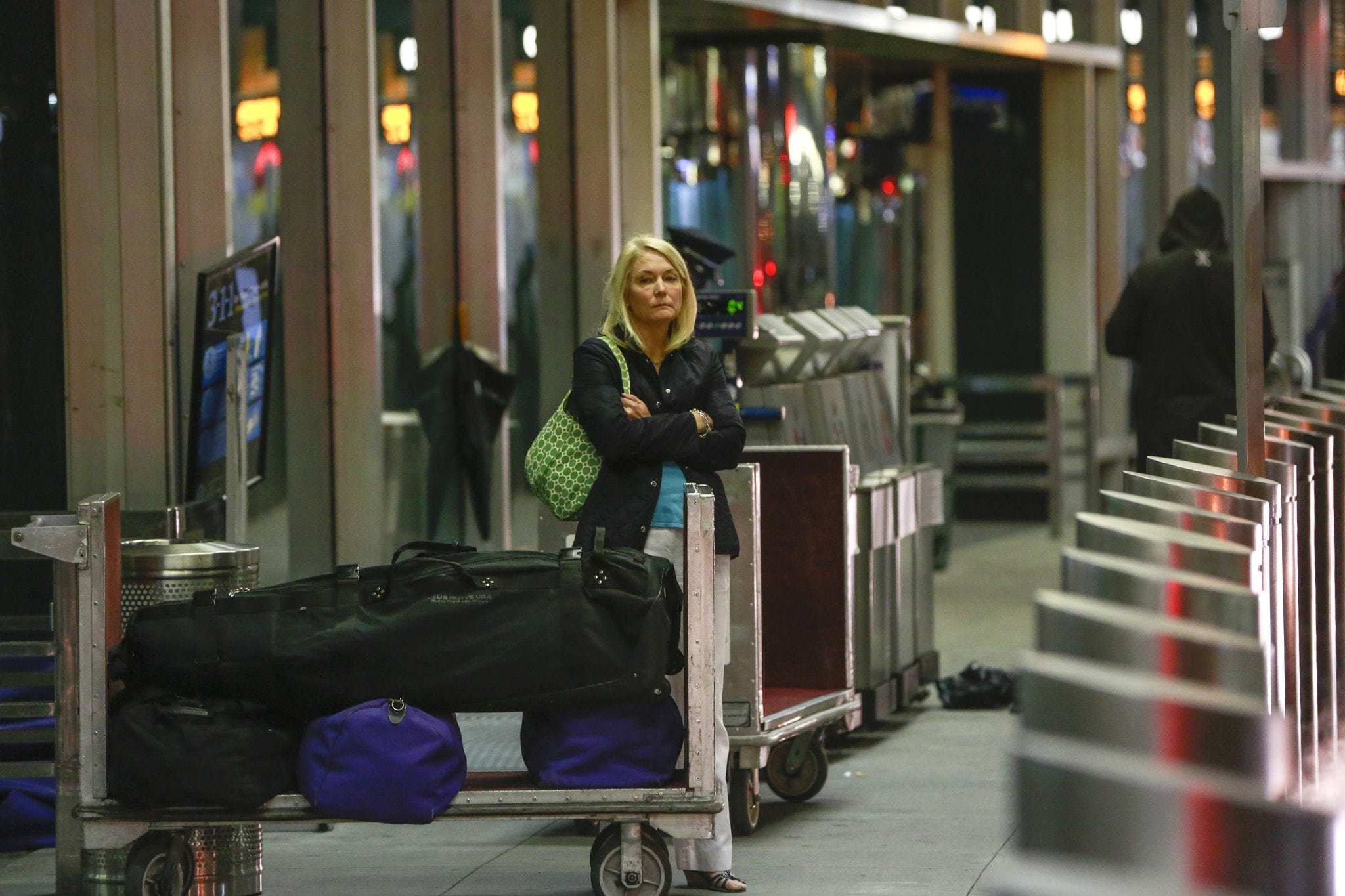 A woman waits with her luggage at a check-in area at LaGuardia Airport in New York, November 26, 2013. 