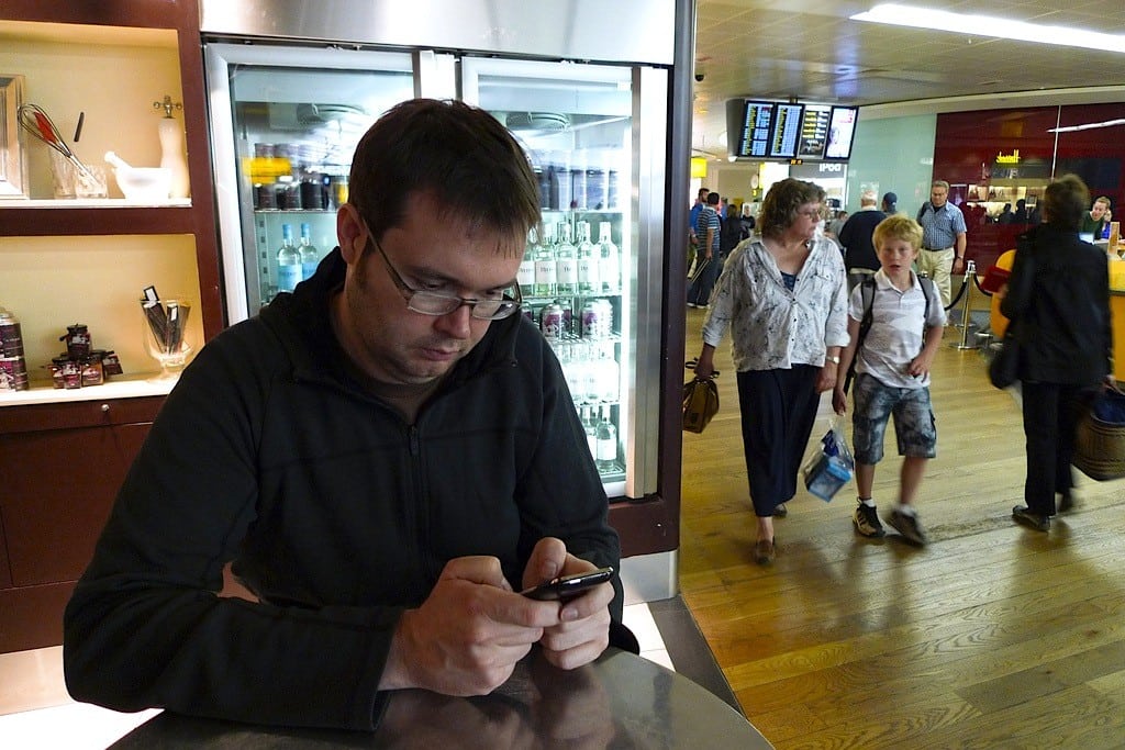 A man looks at his iPhone at the airport. 