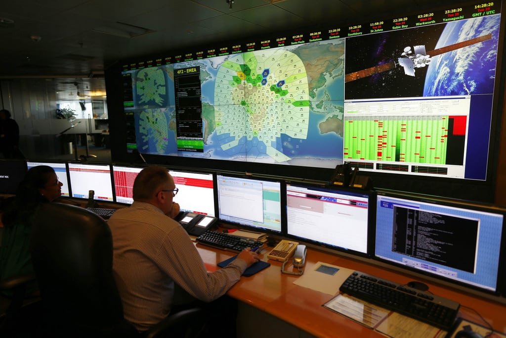 Staff at satellite communications company Inmarsat work in front of a screen showing subscribers using their service throughout the world. 