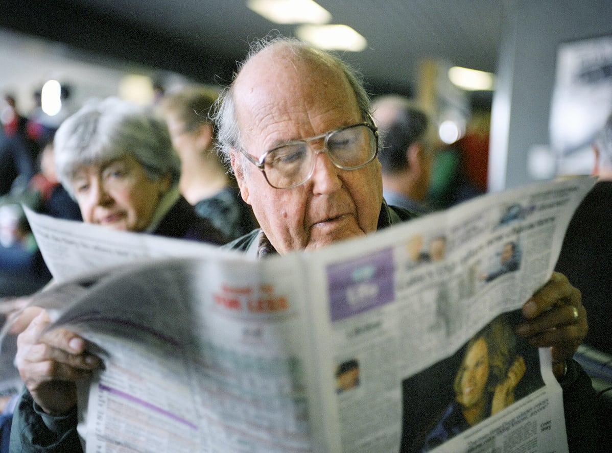 An elderly passenger reading USA Today at SFO Airport, while waiting for the flight.