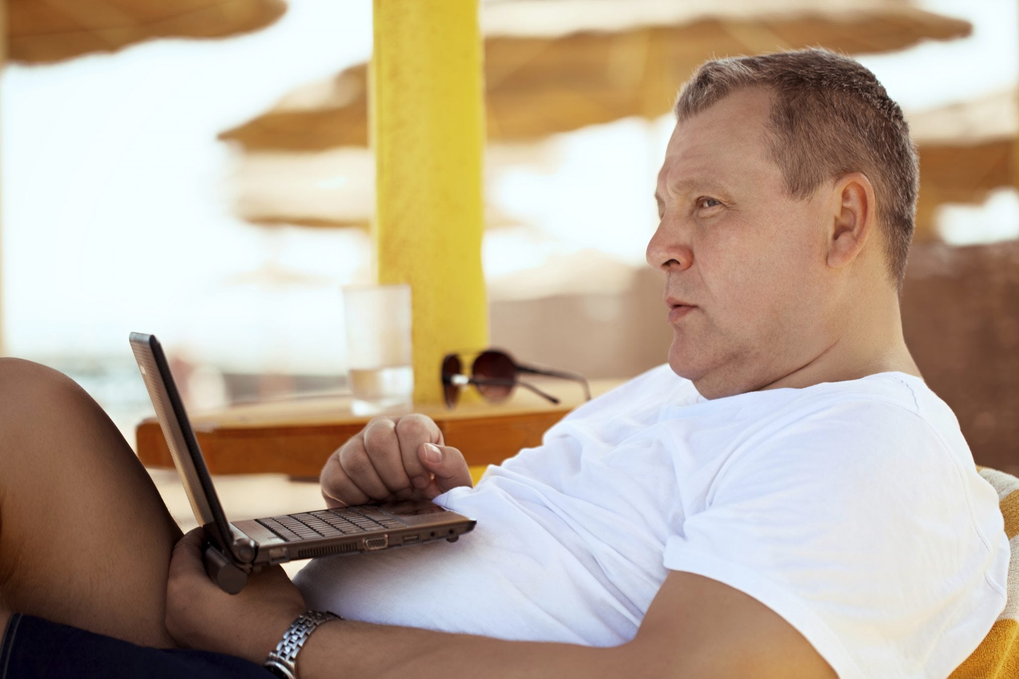 Man relaxes with a laptop at a beach resort.