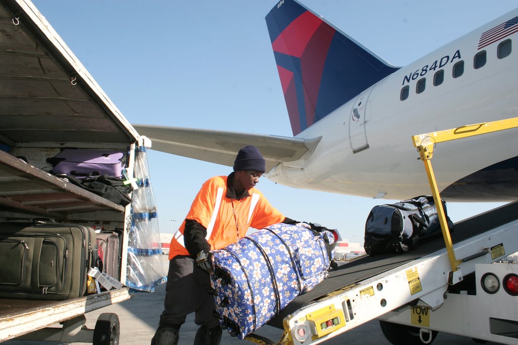 A Delta employee loads bags on plane. 
