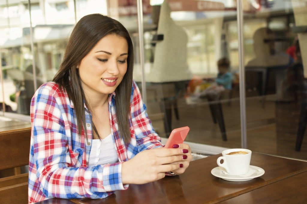 A young women checks her phone at a coffee shop.
