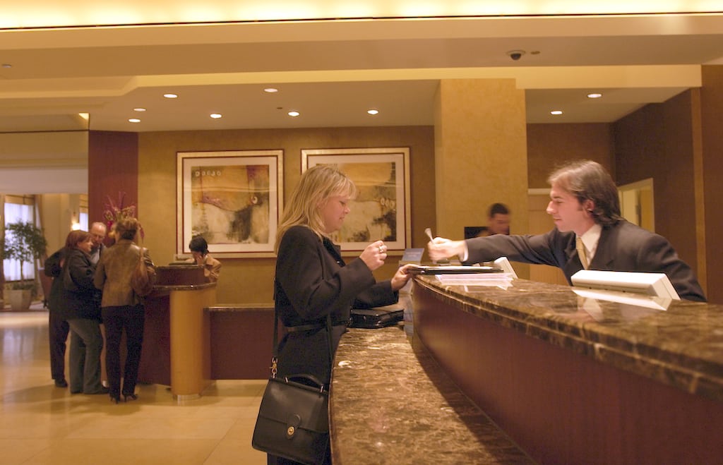 An employee helps a customer check in at a Le Meridien hotel.
