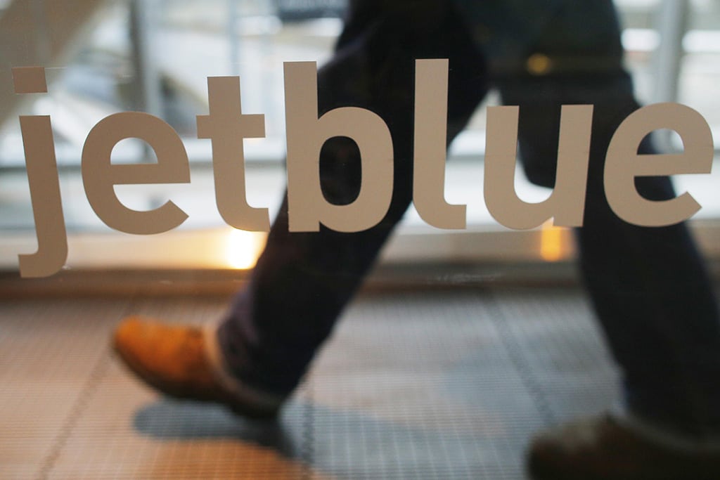 JetBlue's Automatic Check-in service could reduce lines at airport ticket counters. Pictured, a passenger walks past a JetBlue advertisement at Logan International Airport in Boston, Massachusetts. 
